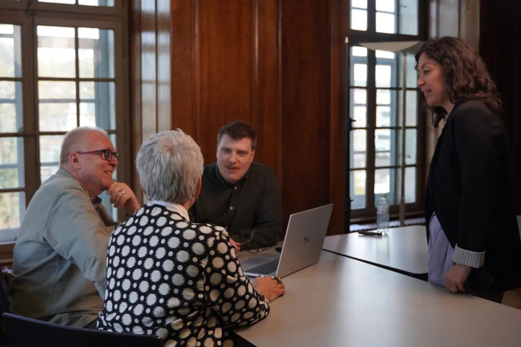 Bau- und Konzeptberatung im Gespräch: vier Personen am Besprechungstisch mit Laptop und Plänen.